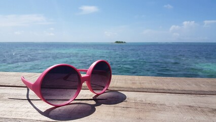 Sunglasses on a wooden bridge against an ocean