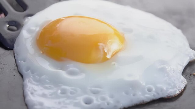 Super close-up of the fried egg taken from the flat grill surface outdoors. High quality 4k footage