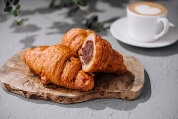 Chocolate-filled croissants on wooden board with coffee