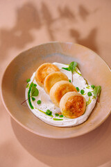 Gourmet cottage cheese pancakes on creamy sauce with greens