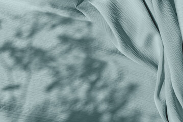 Pastel sage green blue cloth texture with folds and abstract soft floral sunlight shadows,...
