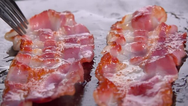 Panorama of appetizing bacon being fried on a stone surface. Close-up. High quality 4k footage