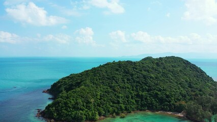 Aerial shot of an island with green nature in the middle of the blue seascape in Asia