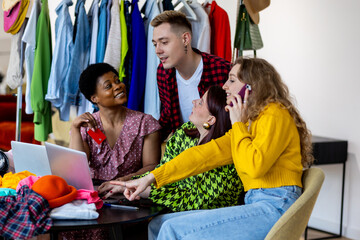 Diverse multicultural group of young women and men shopping online, buying cheap clothes on sales with discounts paying with credit card. Concept of consumerism, fast fashion, over consumption.