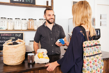 Smiling Customer Making a Credit Card Payment at a Grocery Counter