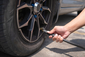 Closeup image of man inflating tire, filling air in the tires of his car. © izzuan