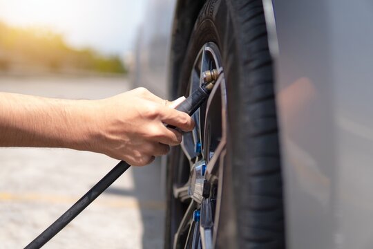 Closeup image of man inflating tire, filling air in the tires of his car.