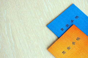 Japanese pension insurance booklets on table. Blue and orange pension book for japan pensioners...