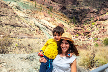 A woman and a child are posing for a picture in front of a rocky mountain