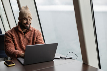 Content Marketer Smiling at Laptop in Coastal Office