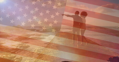 Fototapeta premium Image of flag of united states of america over couple walking on beach