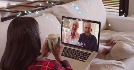 Image of snow falling over happy caucasian woman on laptop image call with her family