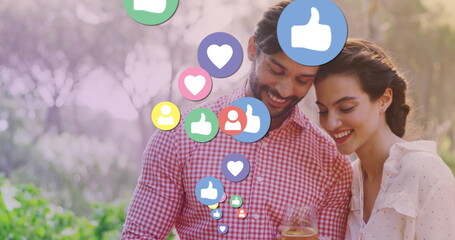 Image of media icons over happy biracial couple using smartphone - Powered by Adobe