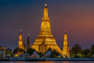 Fototapeta premium Wat Arun stupa, a significant landmark of Bangkok, Thailand, stands prominently along the Chao Phraya River, with a beautiful twilight.