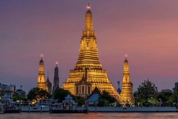 Wat Arun stupa, a significant landmark of Bangkok, Thailand, stands prominently along the Chao Phraya River, with a beautiful twilight.