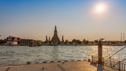 Wat Arun stupa, a significant landmark of Bangkok, Thailand, stands prominently along the Chao Phraya River, with an evening sky. - 785191619