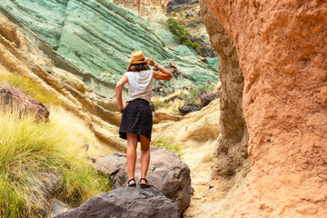 Obraz premium A tourist woman enjoying the natural monument at the Azulejos de Veneguera or Rainbow Rocks in Mogan, Gran Canaria