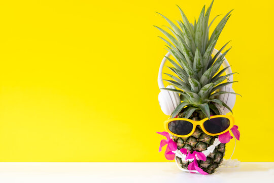Summer in the party.  Hipster Pineapple Fashion in sunglass and listen music bright beautiful color in holiday, Creative art fruit  yellow background.  Summer Vacation Concept, copy space for text
