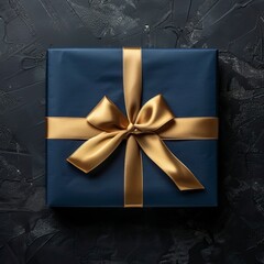 Dark blue gift box with gold satin ribbon on dark background. Top view of birthday gift with copy space