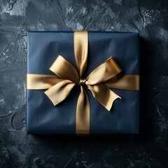 Dark blue gift box with gold satin ribbon on dark background. Top view of birthday gift with copy space