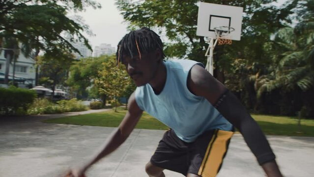 Handheld shot of two male African American athletes playing streetball on playground outdoors
