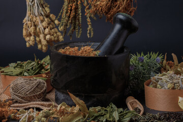 Black Mortar and pestle with dry healthy herbal on dark background. Side view.
