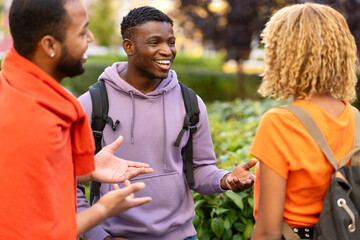 Group smiling stylish African American student with backpacks, talking, walking in university campus