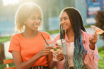 Two smiling African American girls friends, meeting at birthday party, sitting in cafe