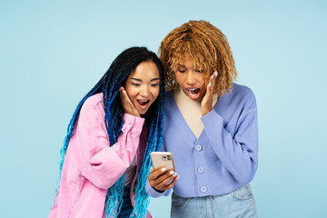 Portrait of overjoyed women friends holding mobile phone shopping online with sales