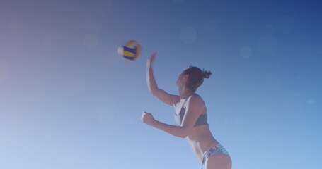 Image of glowing lights over caucasian woman playing beach volleyball by the sea