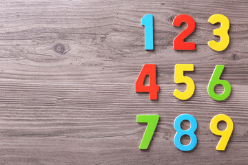 Colorful numbers on wooden school desk, flat lay. Space for text