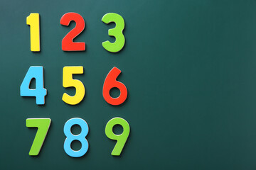 Colorful numbers on green background, flat lay. Space for text