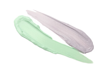 Strokes of green and purple color correcting concealers on white background, top view