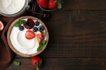 Tasty yogurt, berries, fruits and mint on wooden table, flat lay. Space for text