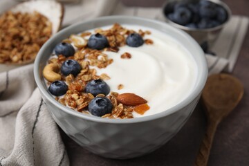 Bowl with yogurt, blueberries and granola on grey table, closeup