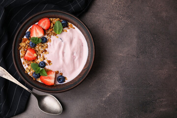 Bowl with yogurt, berries and granola on brown table, flat lay. Space for text