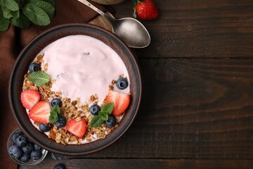 Bowl with yogurt, berries and granola on wooden table, flat lay. Space for text