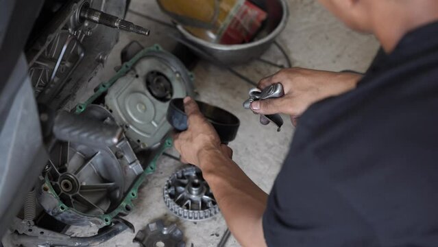 Mechanic cleans motorcycle engine with air blow gun. Mechanic works in motorcycle repair shop. Concept of repair and maintenance service
