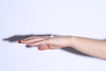 Woman with cream on her hand against white background, closeup