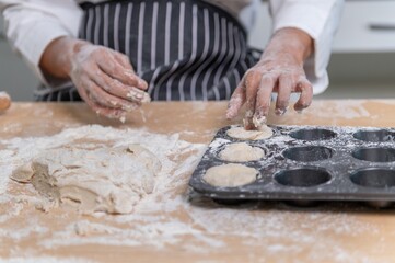 professional Chef sifting flour powder and sprinkling ingredients on massaging dough for bakery cooking. Chef show dirty finger hand sifting flour wheat and kneading dough mixing powder.