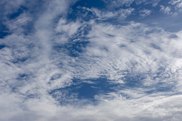 White clouds adorn the blue sky of a beautiful summer sunset.