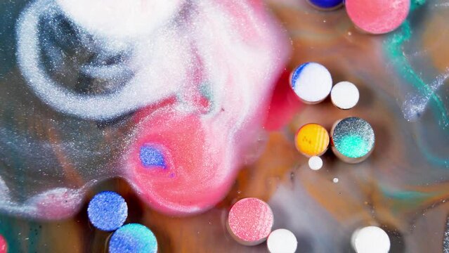 Soluble color tablets dissolving to create liquid ink in abstract art.