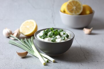 Delicious yogurt with green onion and garlic on light textured table