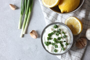 Delicious yogurt, green onion, garlic and lemons on light textured table, top view