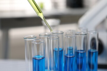 Laboratory analysis. Dripping liquid into test tubes indoors, closeup