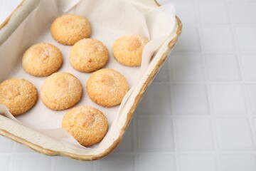 Tasty sweet sugar cookies in baking dish on white tiled table, closeup. Space for text