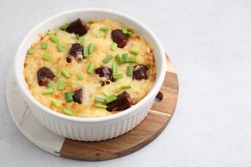 Tasty sausage casserole with green onions in baking dish on white table, closeup
