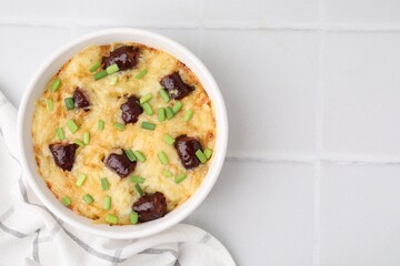 Tasty sausage casserole with green onions in baking dish on white tiled table, top view. Space for text