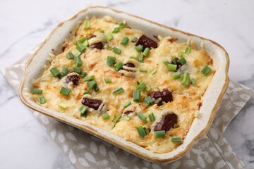 Tasty sausage casserole in baking dish on white marble table, closeup