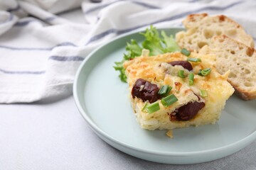 Tasty sausage casserole with green onion and bread on light grey table